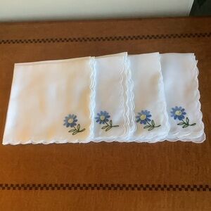 Twelve square white napkins with an Embroidered Blue Flower